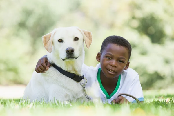 Jongen liggen met zijn huisdier labrador in het park — Stockfoto