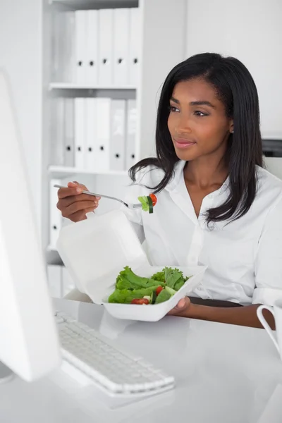 Businesswoman eating a salad at her desk — Stock Photo, Image