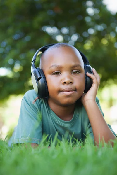 Pojken ligga på gräs som lyssnar på musik — Stockfoto