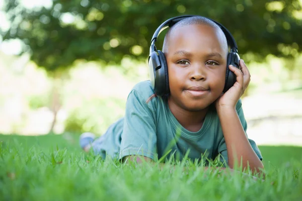 Мальчик лежит на траве и слушает музыку. — стоковое фото