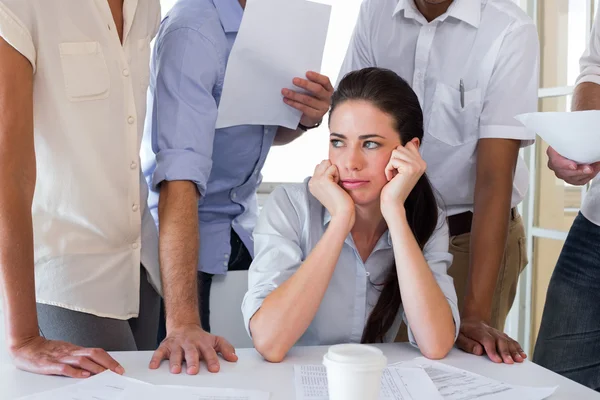 Worried businesswoman surrounded by colleagues — Stock Photo, Image