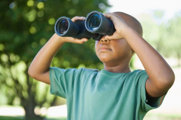 Boy looking up through binoculars in the park — Stock Photo, Image