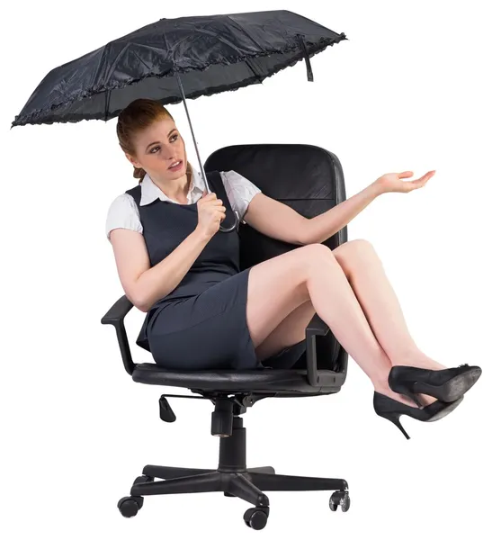 Businesswoman holding umbrella sitting on chair — Stock Photo, Image