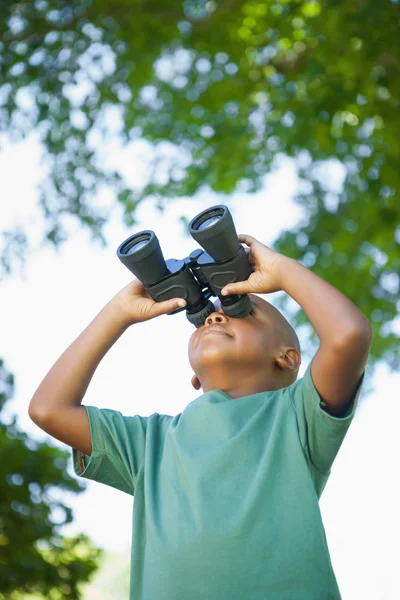 Ragazzo che alza lo sguardo attraverso il binocolo nel parco — Foto Stock