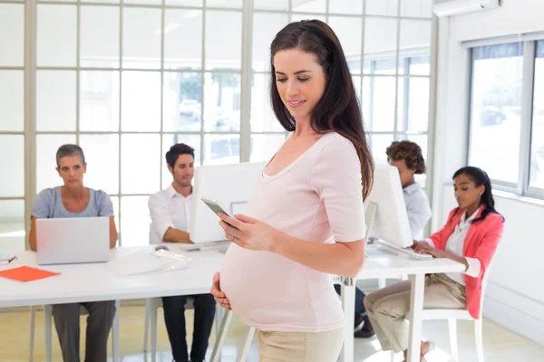 Gravid kontor arbetaren texter på telefon — Stockfoto