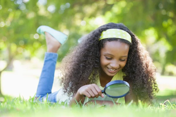 Flicka genom förstoringsglas i parken — Stockfoto