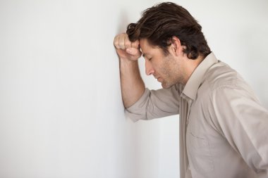 Worried businessman leaning head on wall clipart
