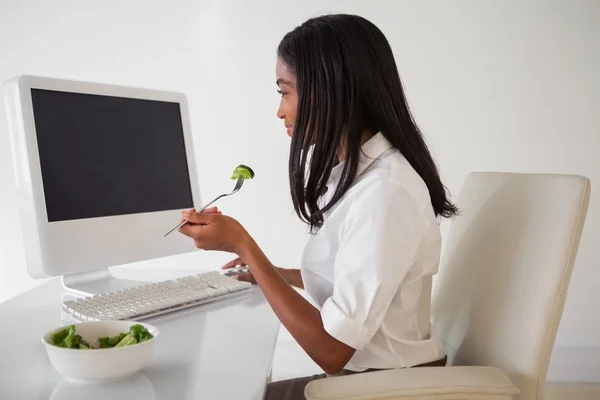 Businesswoman eating a salad at her desk — Stock Photo, Image