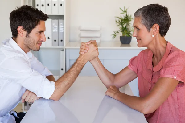 Business team arm wrestling at desk — Stock Photo, Image