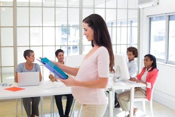 Embarazada mujer de negocios llevando carpeta — Foto de Stock