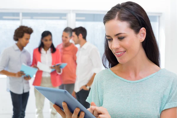 Empresária usando tablet com colegas de trabalho atrás — Fotografia de Stock