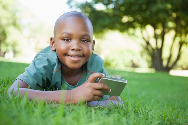 Garçon sur herbe tenant appareil photo numérique — Photo