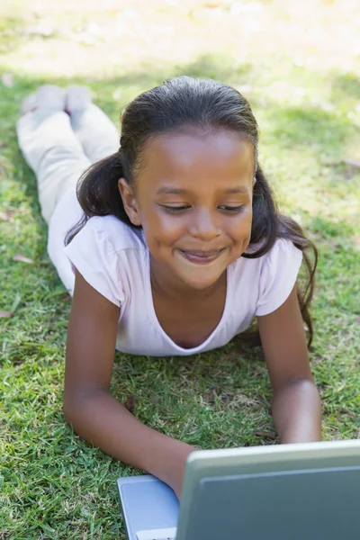 Flickan liggande på gräs med laptop — Stockfoto