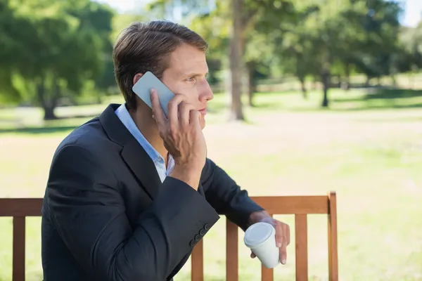Бизнесмен разговаривает по телефону на скамейке — стоковое фото