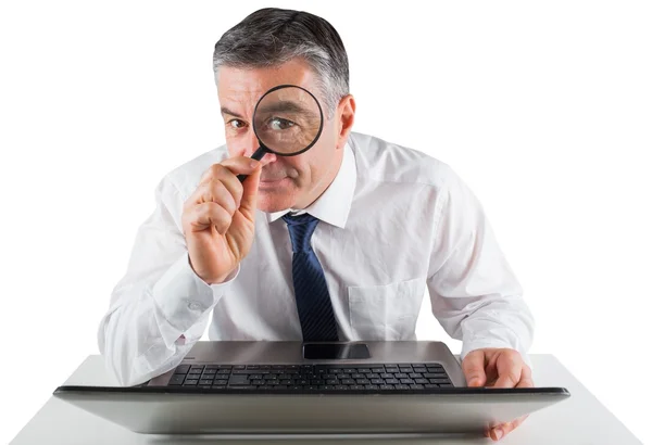 Businessman examining with magnifying glass — Stock Photo, Image