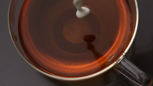 Milch gießt in Tasse Tee — Stockvideo
