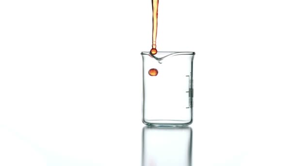 Líquido naranja vertiendo en el vaso de precipitados — Vídeo de stock