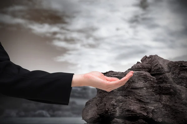 Businesswomans hand presenting against large rock — Stock Photo, Image