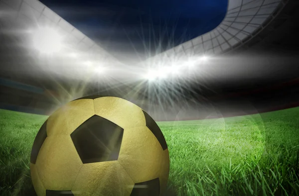 Gold football against football pitch — Stock Photo, Image