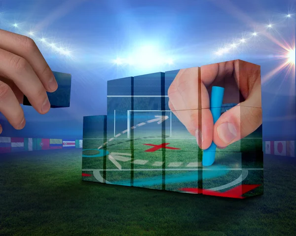 Hand building wall against football pitch — Stock Photo, Image