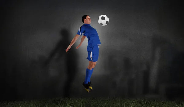 Football player in blue jumping — Stock Photo, Image