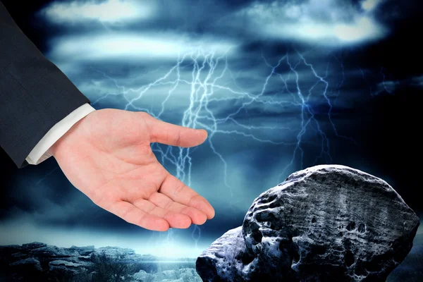 Businessmans hand presenteren tegen grote rots — Stockfoto