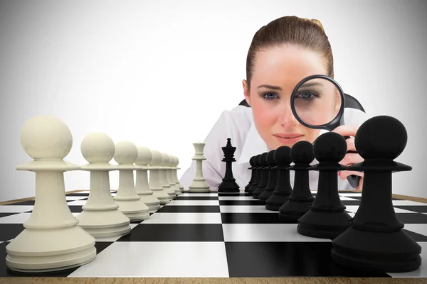 Businesswoman with magnifying glass with chessboard — Stock Photo, Image