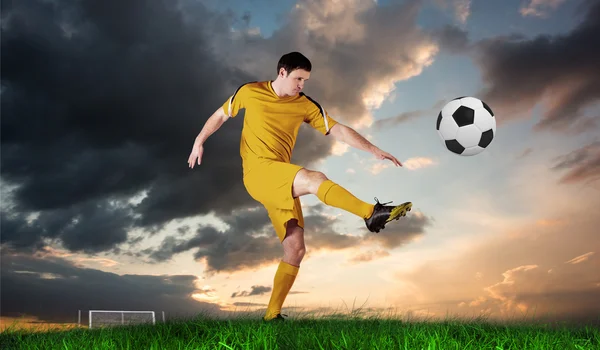 Jogador de futebol em amarelo chutando — Fotografia de Stock