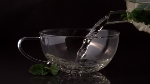 Teapot pouring mint tea into cup — Stock Video