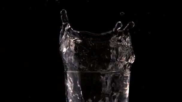 Ледяной куб падает в стакан воды — стоковое видео