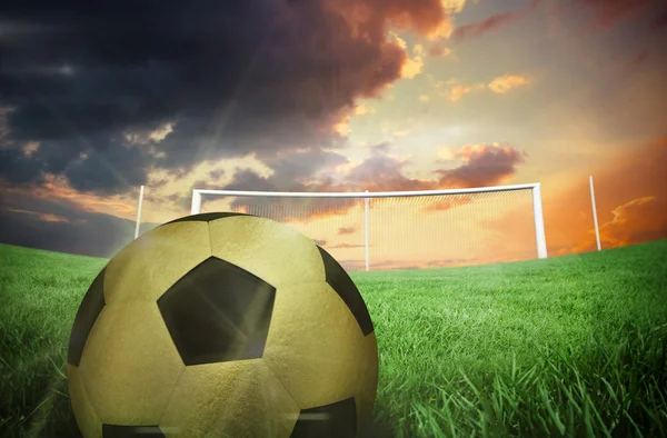 Gold football against football pitch — Stock Photo, Image