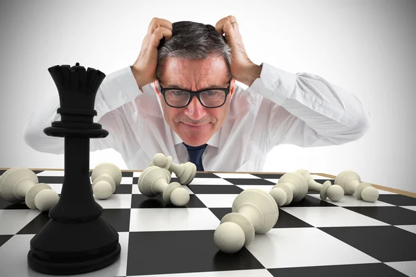 Empresário tocando sua cabeça com tabuleiro de xadrez — Fotografia de Stock