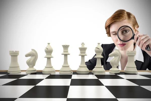 Businesswoman with magnifying glass with chessboard — Stock Photo, Image