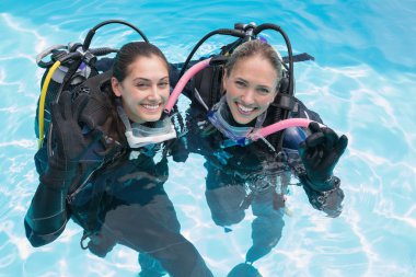 Friends on scuba training in swimming pool clipart
