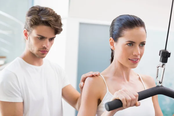 Vrouw met behulp van gewichten machine met traine — Stockfoto