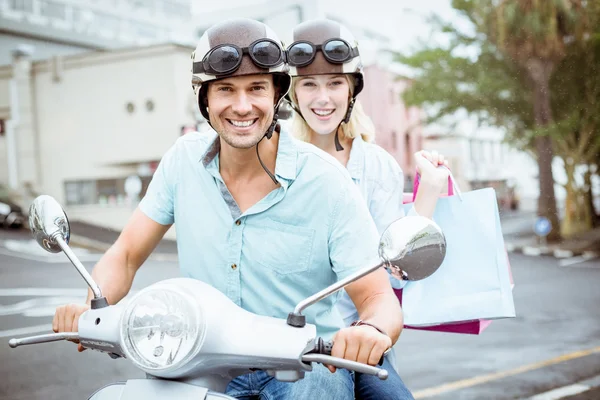 Couple riding scooter with shopping bags — Stock Photo, Image