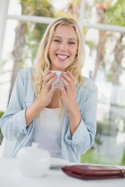 Blonde zitten aan tafel met koffie — Stockfoto