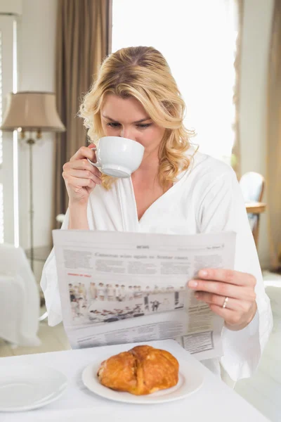 Blondine trinkt Kaffee, liest Zeitung — Stockfoto