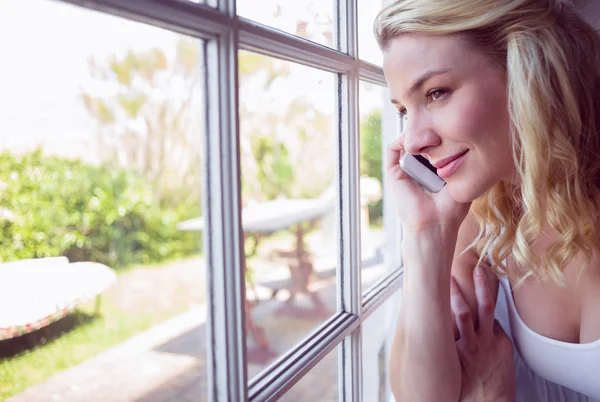 Блондинка біля вікна на телефонний дзвінок — стокове фото