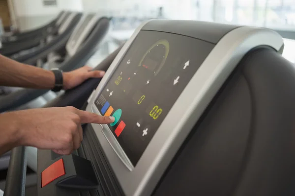 Man adjusting settings on treadmill — Stock Photo, Image