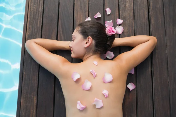 Brunette au bord de la piscine avec pétales de rose — Photo