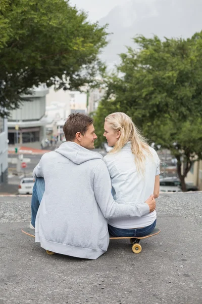 Couple sitting on skateboard — Stock Photo, Image