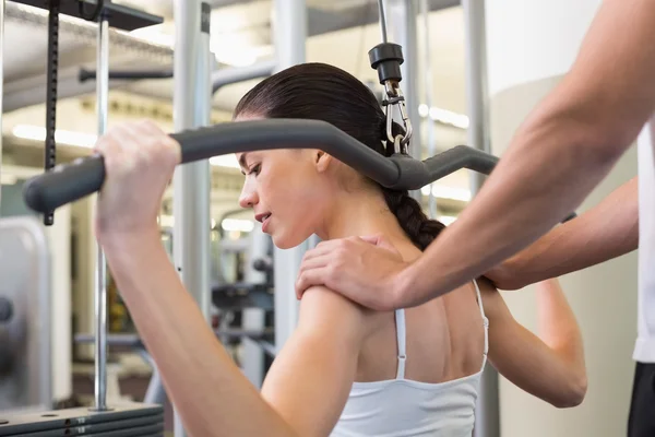 Brunette using weights machine with trainer — Stock Photo, Image