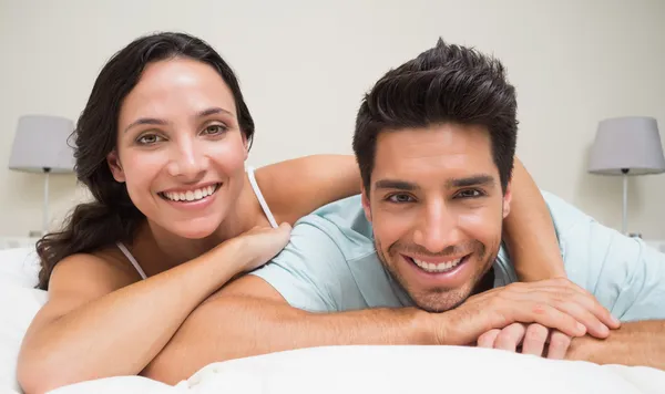 Paar liegt auf Bett und lächelt in die Kamera — Stockfoto