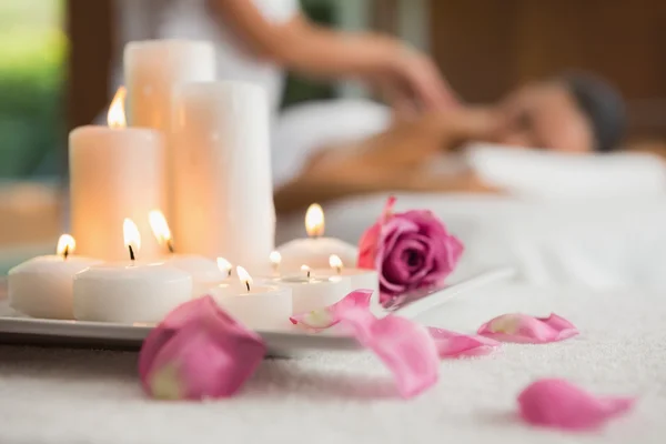 Velas e pétalas de rosa na mesa de massagem — Fotografia de Stock