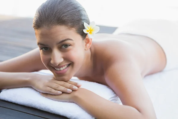 Happy brunette lying on a towel poolside — Stock Photo, Image