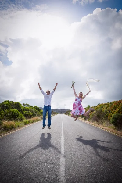 Pareja emocionada saltando en la carretera — Foto de Stock