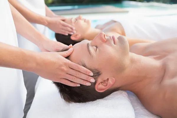 Couple enjoying head massages poolside — Stock Photo, Image