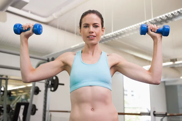 Woman lifting blue dumbbells — Stock Photo, Image