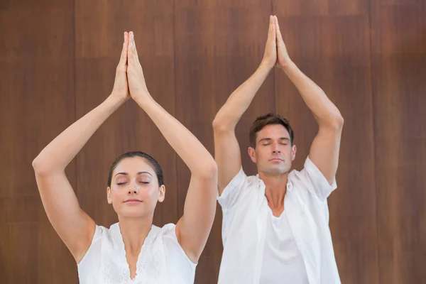 Pareja haciendo yoga con las manos levantadas — Foto de Stock
